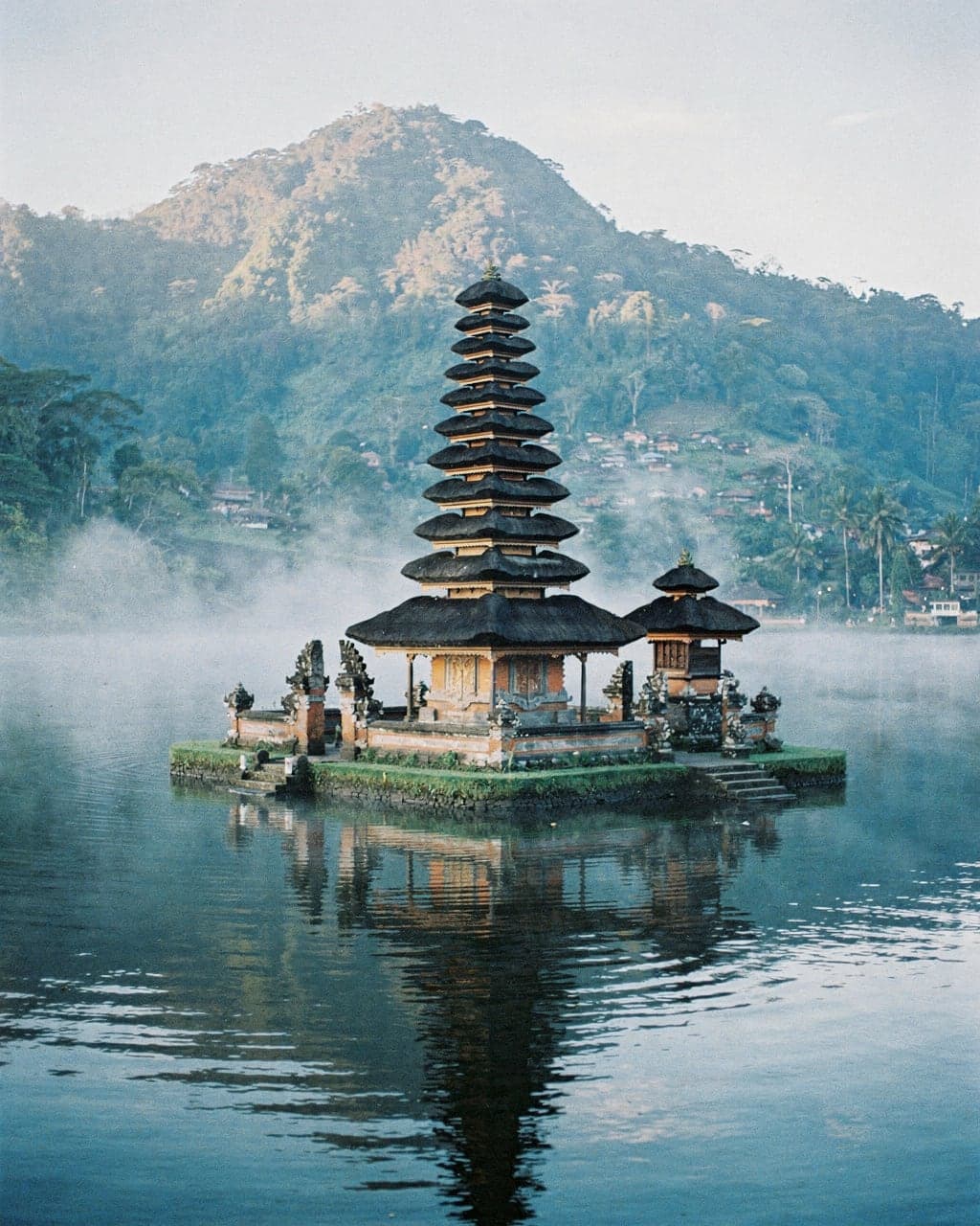 The tiered thatched shrine of Ulun Danu Beratan temple standing on misty Lake Beratan in the early morning