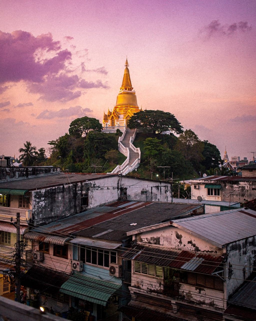 The gilded chedi of the Golden Mount at Wat Saket on its hill at dusk, with old-town rooftops spreading out below