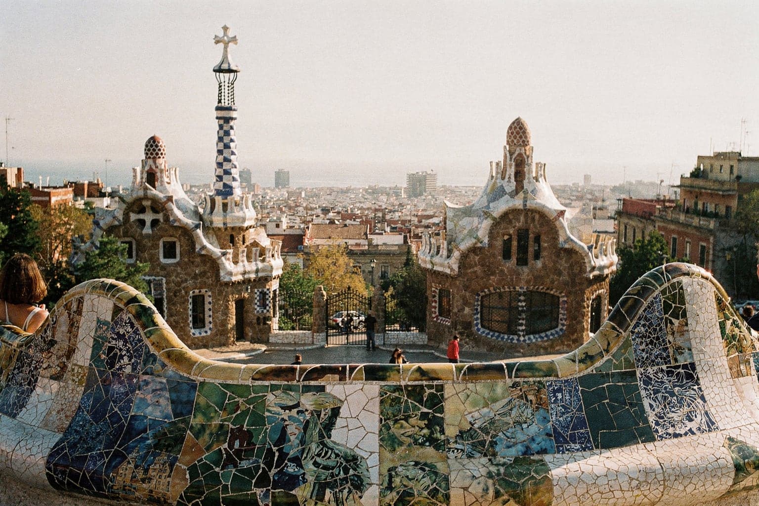 The curving mosaic bench on Park Güell's main terrace with the city and the sea beyond