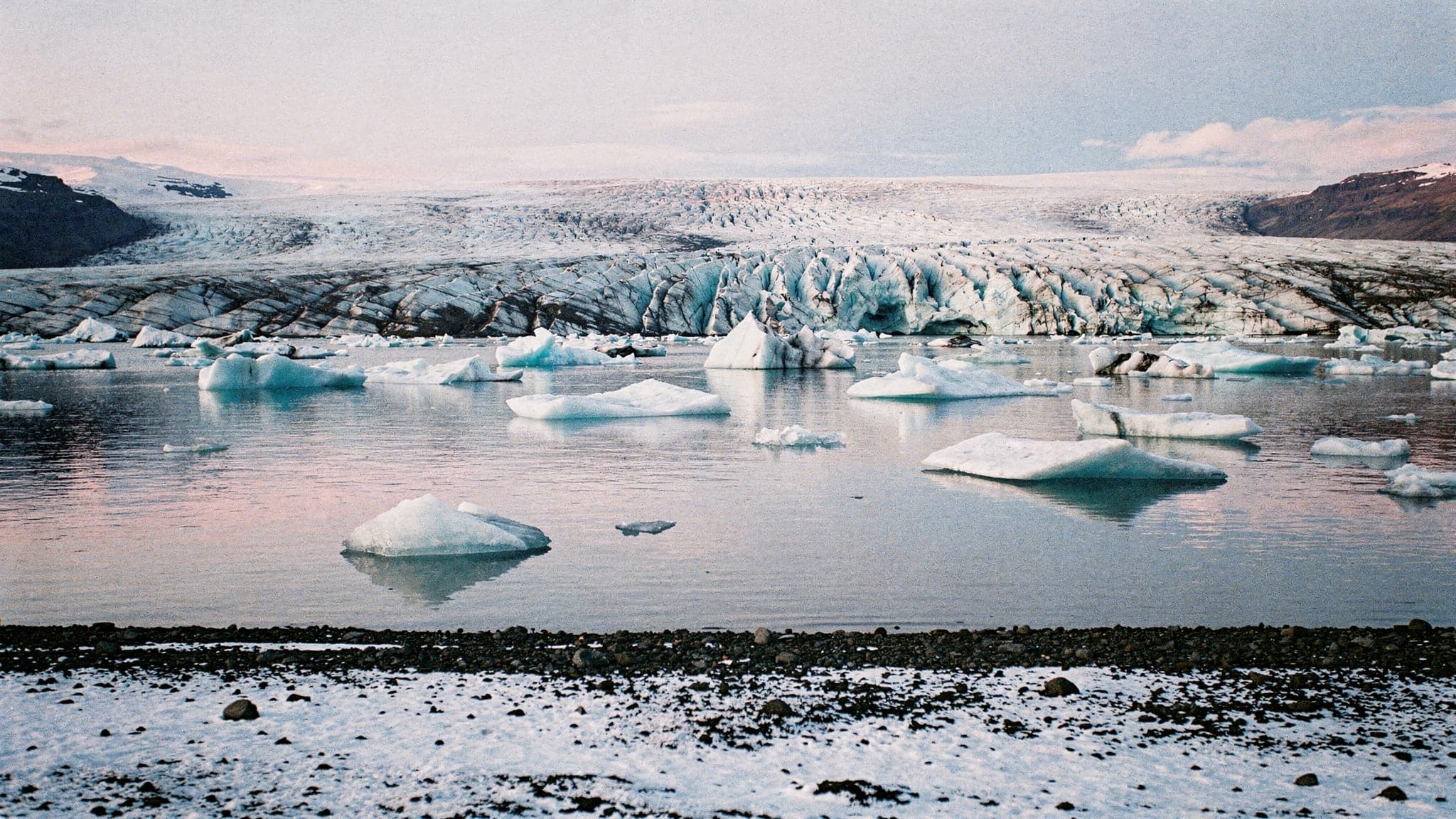 Icebergs drifting on Jökulsárlón glacier lagoon at sunrise, with the Breiðamerkurjökull glacier behind