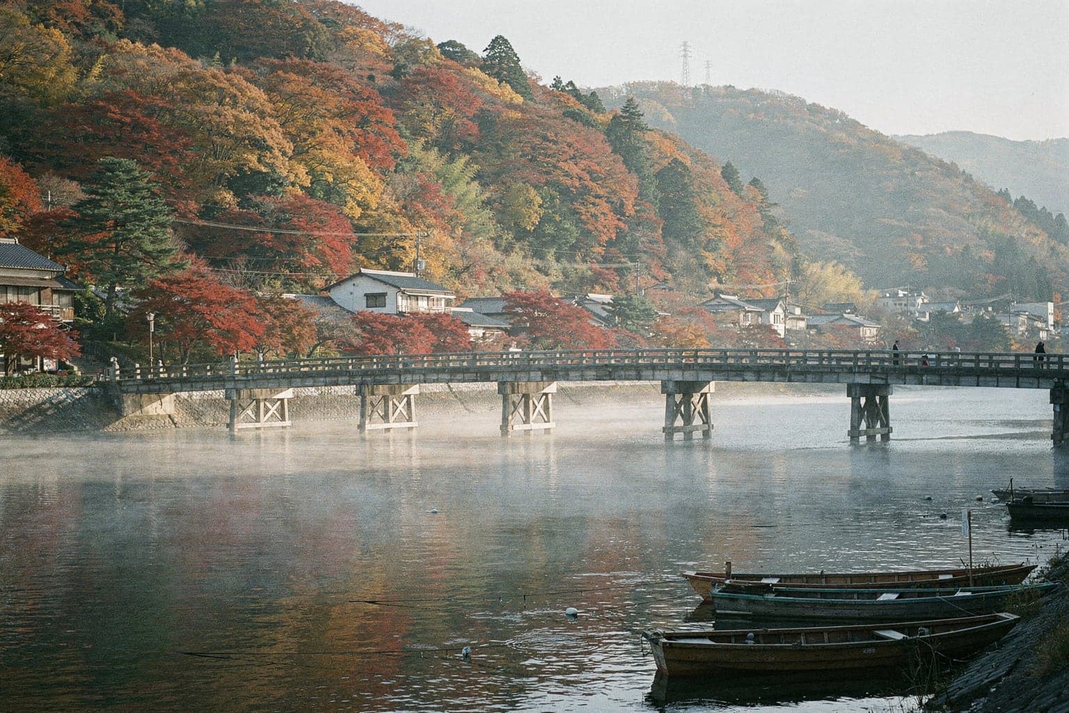 Togetsukyo Bridge crossing the Katsura River in Arashiyama, with maple-covered hills in red and orange behind it