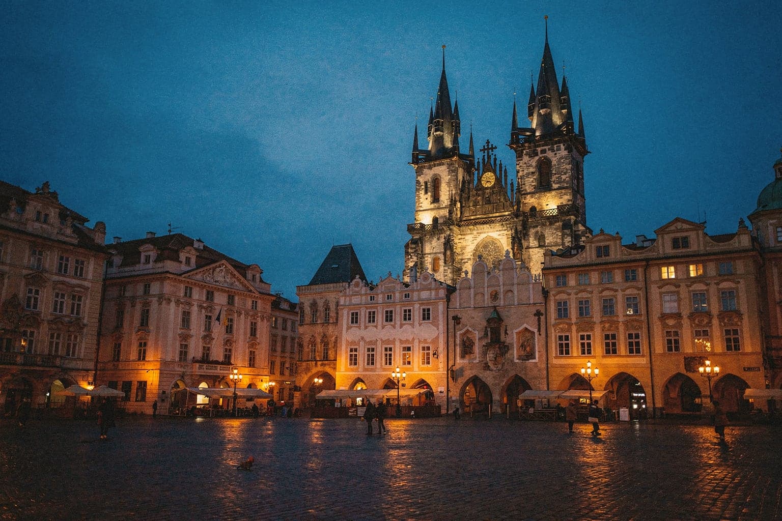 The floodlit twin spires of Týn Church above Old Town Square in Prague at dusk