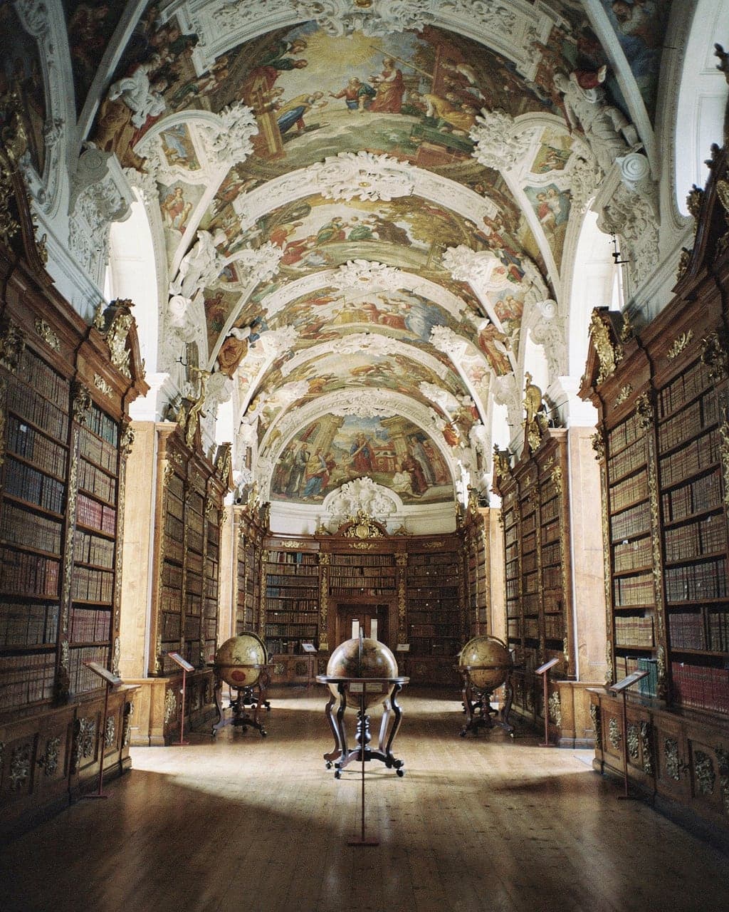 The frescoed vaulted ceiling and gilded bookcases of the Theological Hall at Strahov Library